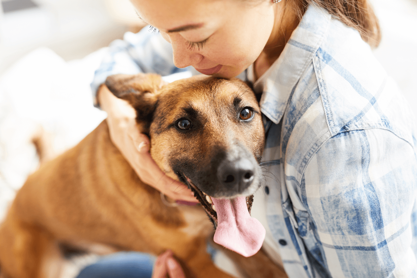 a fotón egy fiatal nő látható, aki kutyáját magához öleli, a kutyának nyitott a szája és kilóg a nyelve.